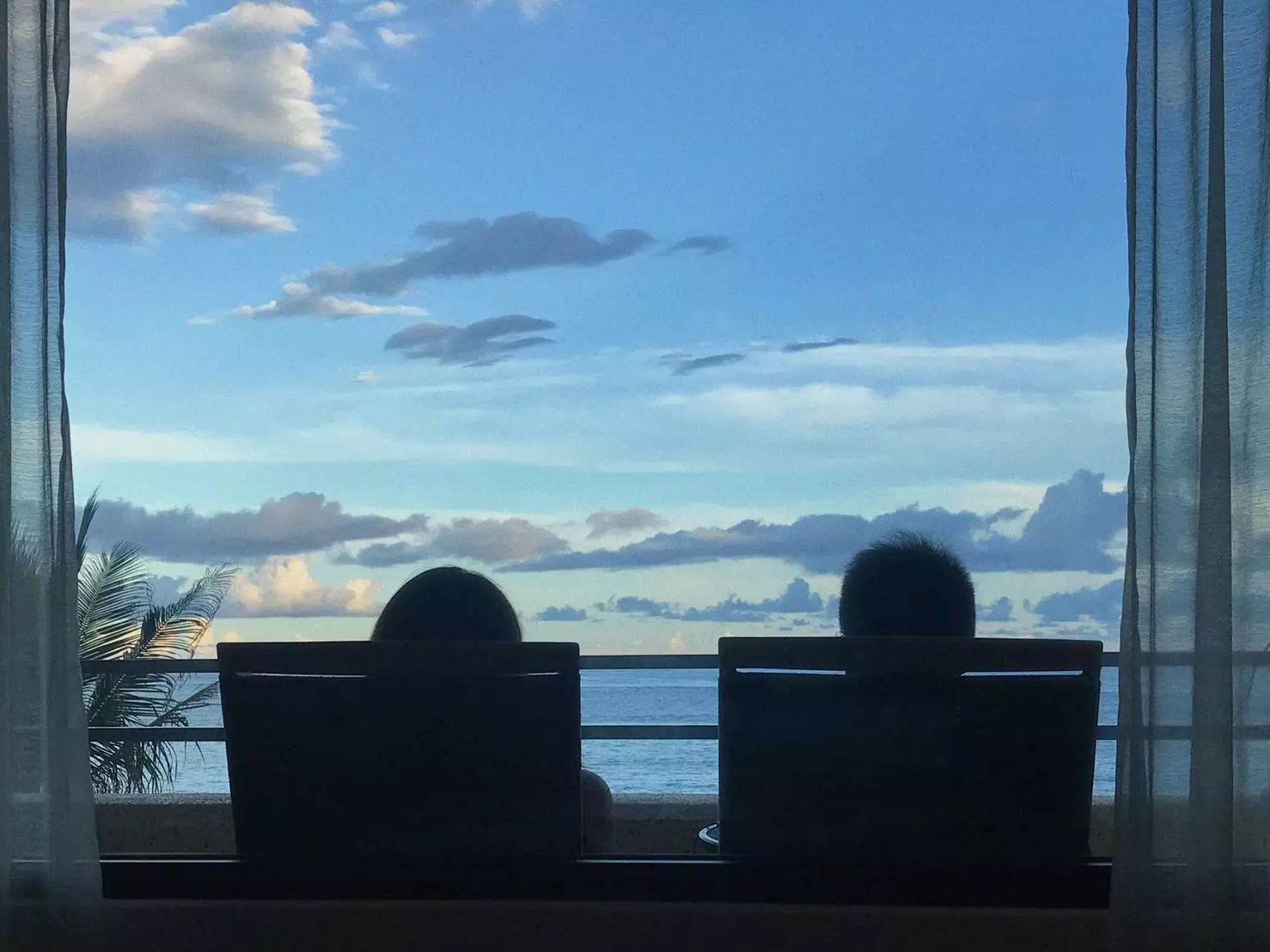 兩個人坐在窗前看海的剪影